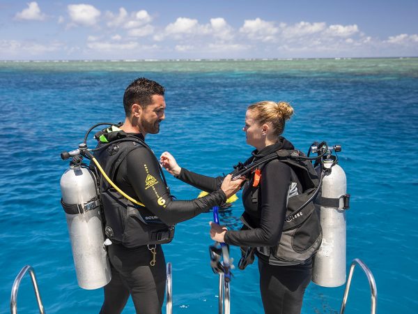 Passions of Paradise couple doing scuba safety check