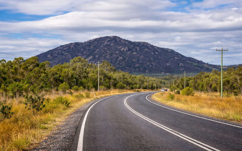 Open savannah along the Mulligan Highway heading north toward Cooktown, with Black Mountain visible in the distance