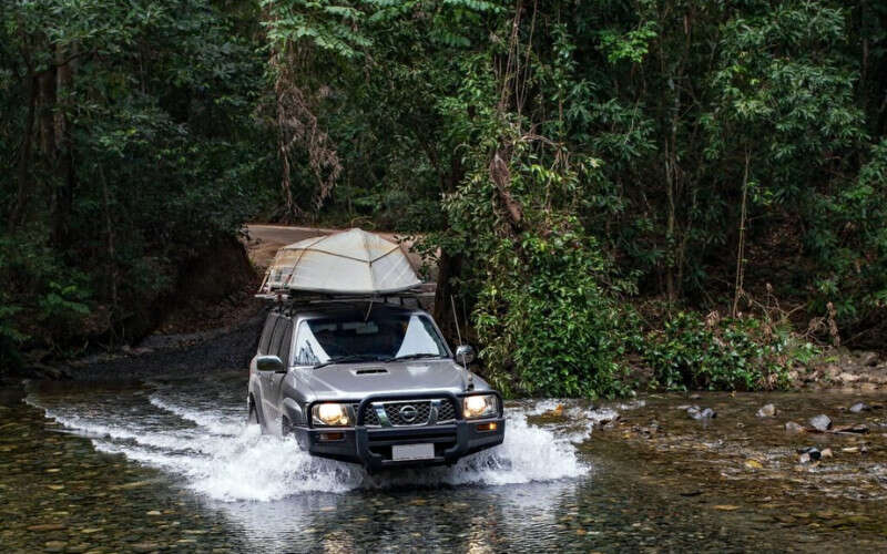 Purpose-built 4WD vehicle on the Bloomfield Track, Far North Queensland, surrounded by rainforest
