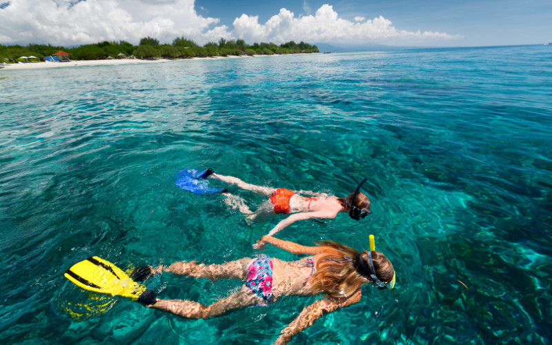 Two people snorkelling in clear shallow water at the Great Barrier Reef