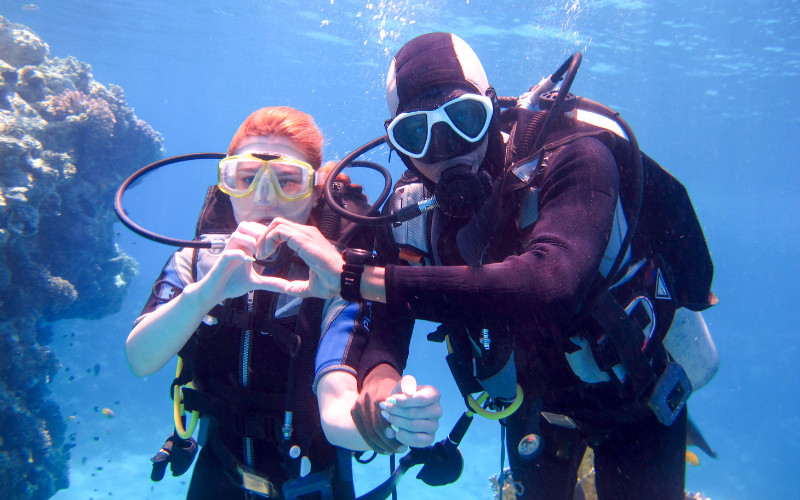 Instructor and new diver underwater making a hand signal during intro dive