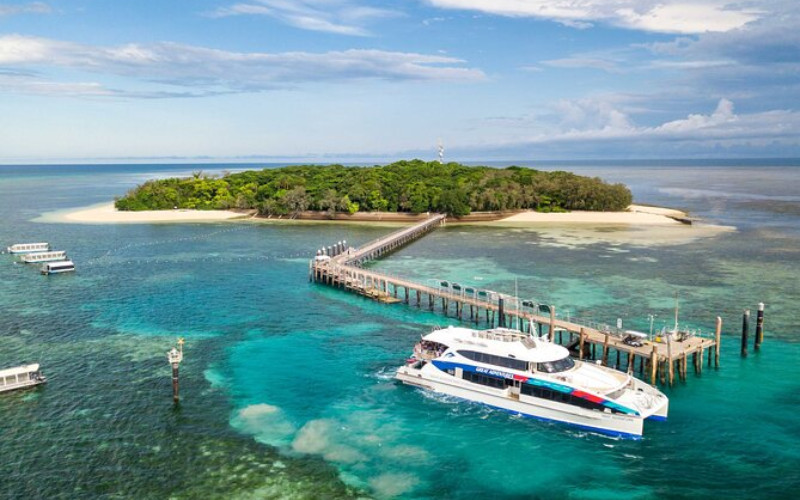 Aerial view of ferry at Green Island with sandy beaches, jetty and coral reef lagoon