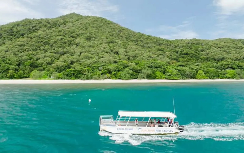 Boat cruising past Fitzroy Island shoreline with green hills and turquoise water