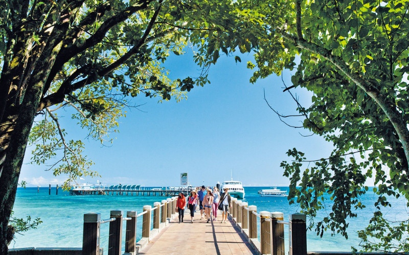 Group of tourists strolling on a pier toward Green Island surrounded by clear blue water