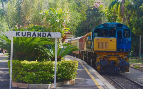 Scenic Railway train arriving at Kuranda station sign surrounded by tropical gardens Queensland