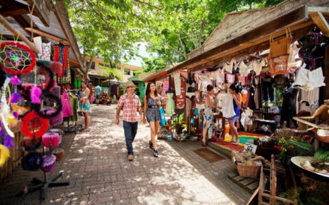 `Couple browsing Kuranda Original Markets stalls with handmade crafts and souvenirs Queensland Australia`