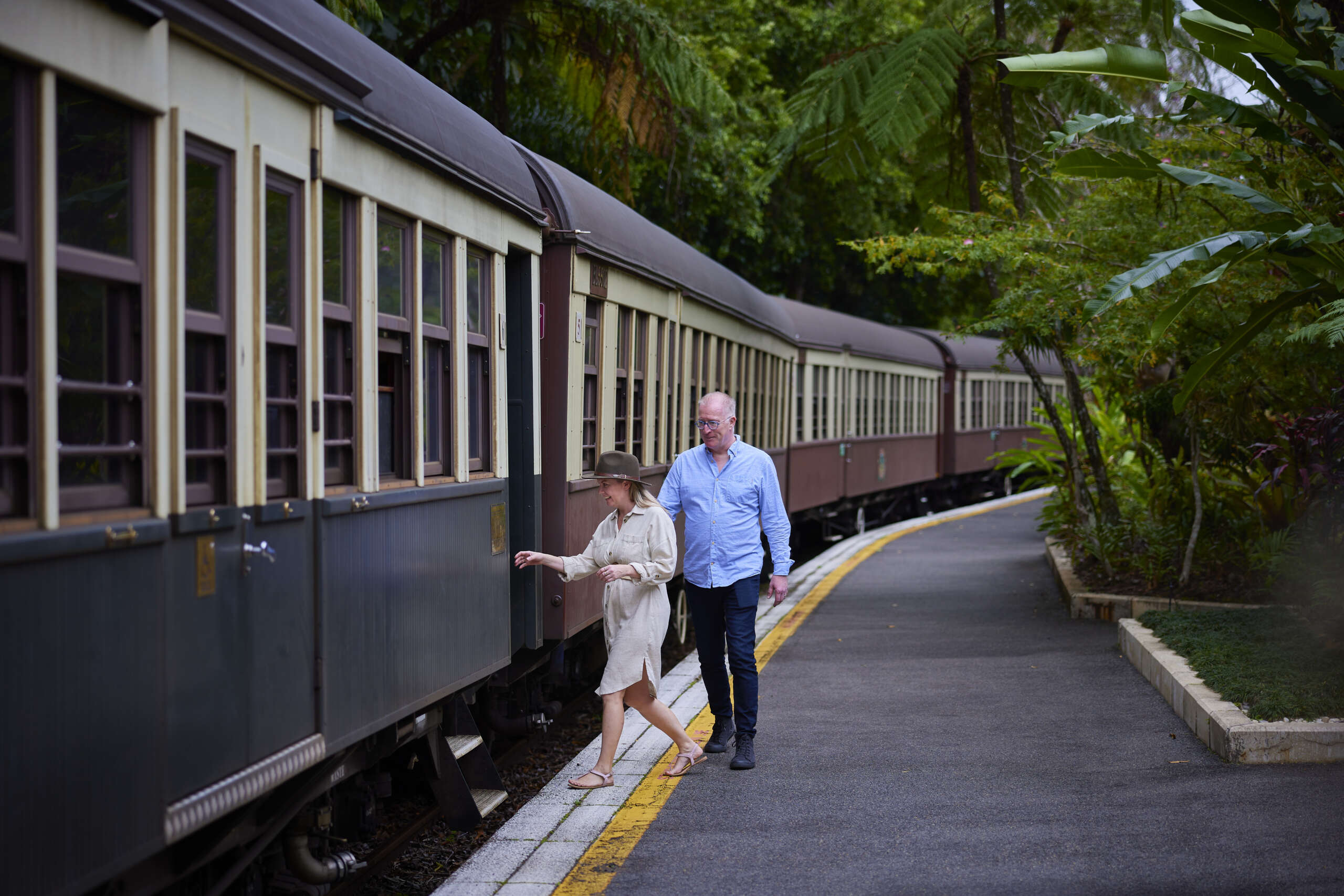 Couple boarding Kuranda Scenic Railway heritage train at rainforest station Queensland Australia