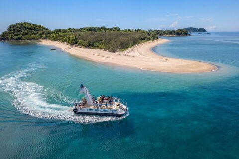 `Frankland Islands tour boat approaching secluded sandy beach and coral reef near Cairns Queensland`