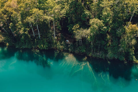 `Aerial view of crystal clear turquoise water at Lake Eacham volcanic crater lake Atherton Tablelands Queensland`