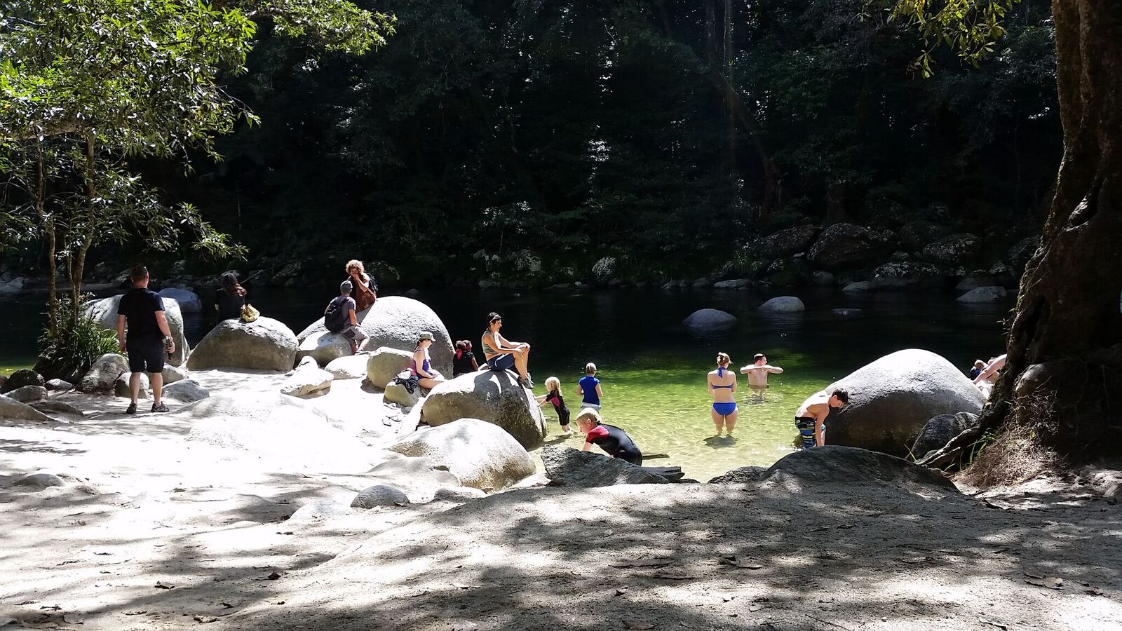 Visitors swimming and relaxing on granite boulders at Mossman Gorge natural river pools Daintree National Park Queensland