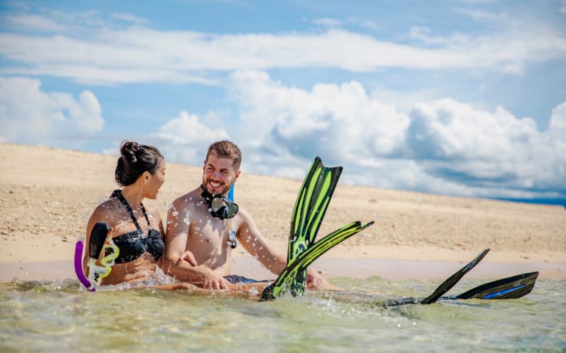 Couple with snorkel gear on Great Barrier Reef sandbank near Cairns Queensland Australia