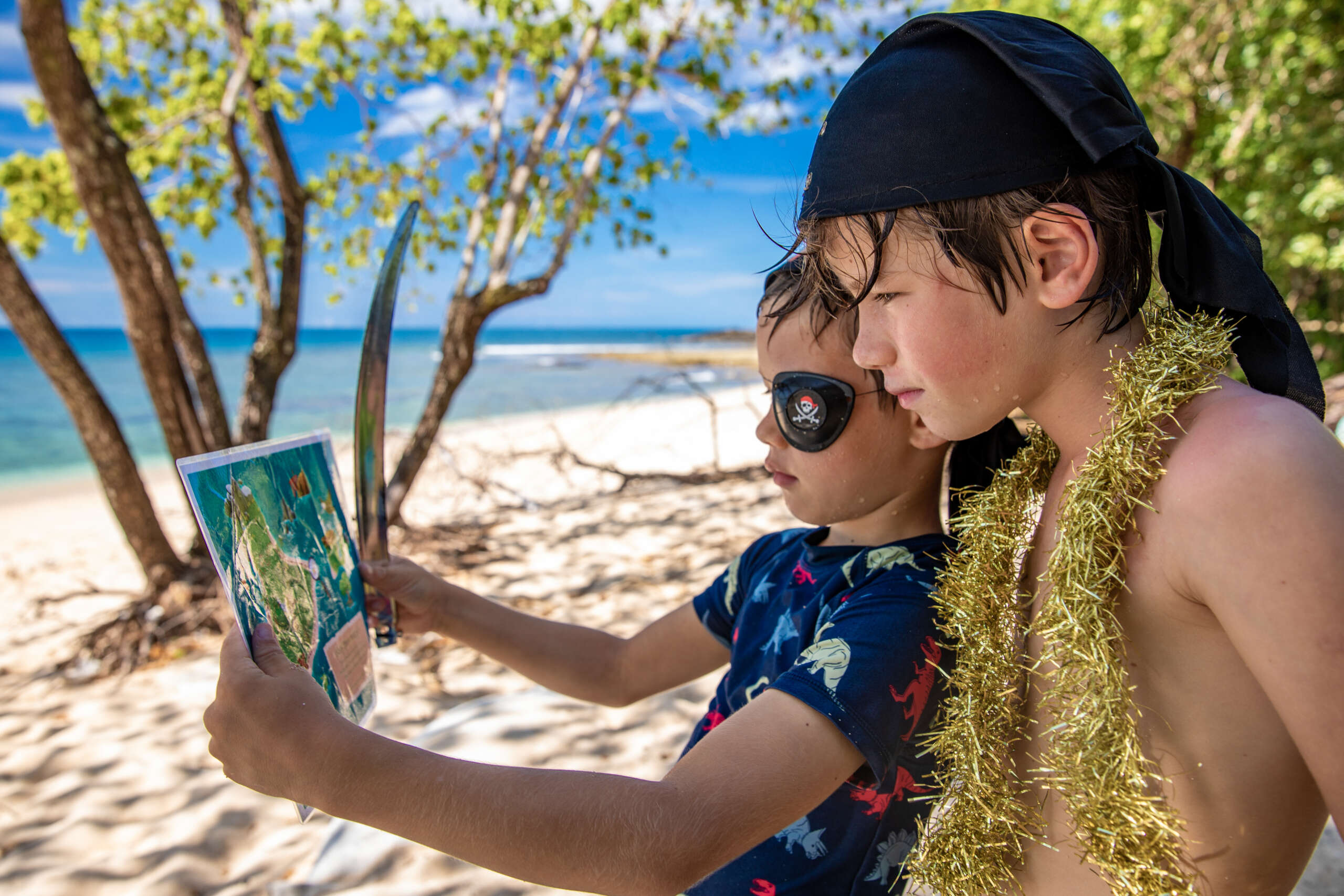 Children in pirate costumes reading treasure map on Frankland Islands beach day trip Cairns Queensland