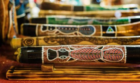 Close-up of hand-painted Aboriginal-style didgeridoos with intricate patterns, displayed at a market stall.